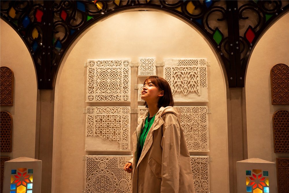 زائرة يابانية تتأمل النقوش اليمنية في إكسبو أوساكا — A Japanese visitor exploring Yemeni ornament at Expo Osaka